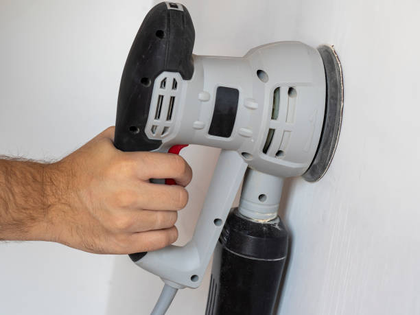 istock a Builder uses a sander to process a white concrete wall. Construction concert 1295988671