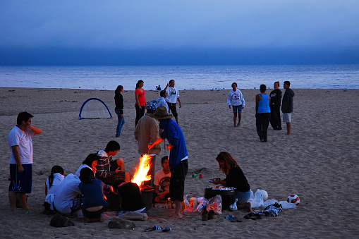Santa Cruz, CA, USA August 12 Friends gather around a bonfire on the beach at Twin Lakes State Park in Santa Cruz, California