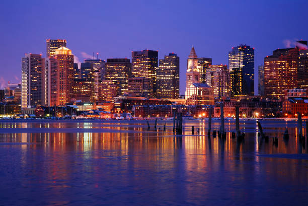 Boston skyline reflected The lights of the Boston skyline are reflected in the icy waters of the harbor boston skyline night skyscraper stock pictures, royalty-free photos & images