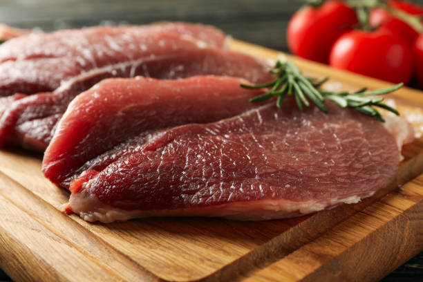 istock Board with fresh raw steak meat on wooden background 1295990844