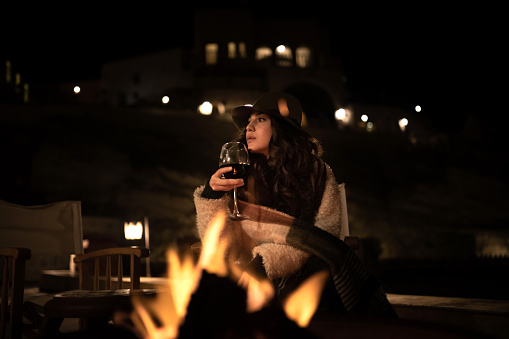 Young beautiful woman sitting by the fire at night alone.