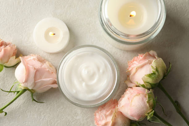 istock Scented candles, cosmetic cream and roses on white table 1295991951