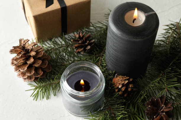 istock Scented candles, gift box and pine branches with cones on white table 1295992467