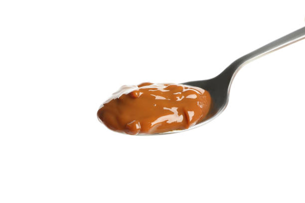 istock Spoon with caramel condensed milk isolated on white background 1295992599