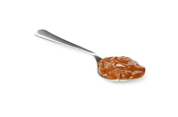 istock Spoon with caramel condensed milk isolated on white background 1295993161