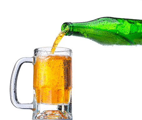 Pouring beer from a green bottle to a glass. The bottle and the glass are cold and drops are visible on them High resolution studio digital capture taken with Sony A7rII and Sony FE 90mm f2.8 macro G OSS lens