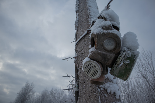 old gas mask hanging on a pole in winter. snow covered.