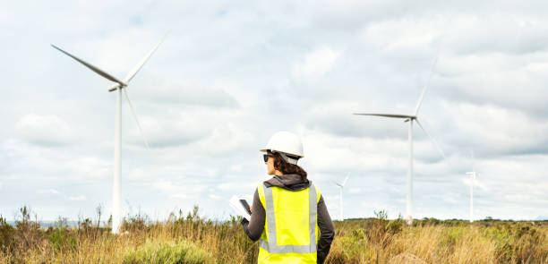istock Engineer standing outside looking at turbines on a wind farm 1295996623