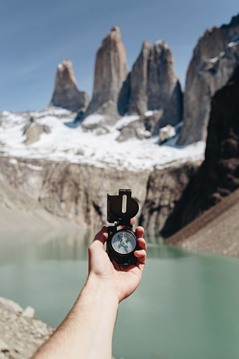 Man holds a compass at scenic view of Torres del Paine National Park background
