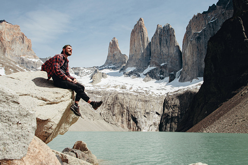 Caucasian Man is sitting at scenic view of Torres del Paine National Park background