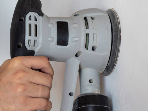 istock a Builder uses a sander to process a white concrete wall. Construction concert 1295999547