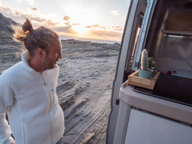 istock Man walks back to his van, sunset on coastline 1296000601