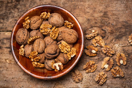 Healthy walnut kernels in a bowl on a rustic table top view