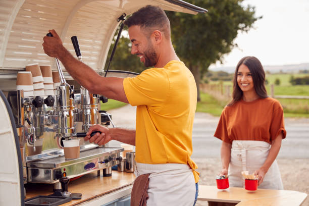 istock Couple Running Independent Mobile Coffee Shop Preparing Drink Standing Outdoors Next To Van 1296002455