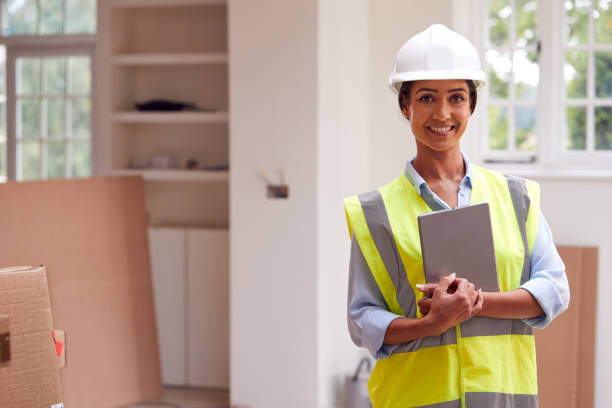 retrato de la mujer topónla de edificio que lleva un sombrero duro con la tableta digital mirando a la nueva propiedad - inspector safety construction reflective clothing fotografías e imágenes de stock