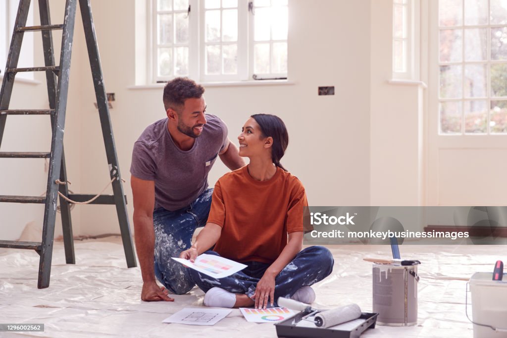 Couple Sitting On Floor With Paint Chart Ready To Decorate New Home Home Improvement Stock Photo