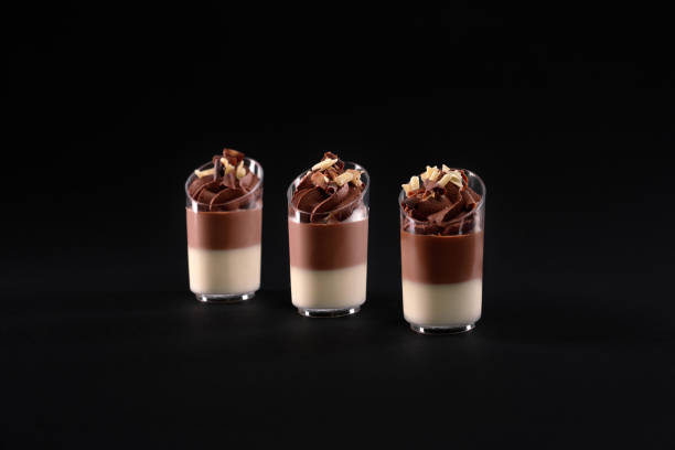 istock Layered creamy panna cotta in glasses isolated on black. 1296003676
