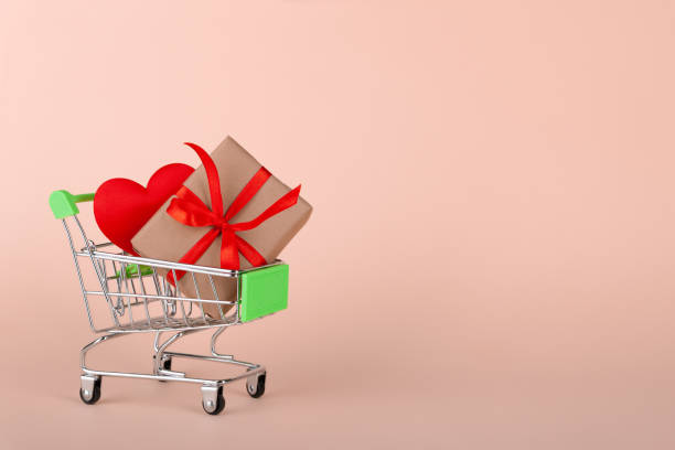 istock Red heart, gift box with red ribbon inside mini grocery cart on colored background 1296003868