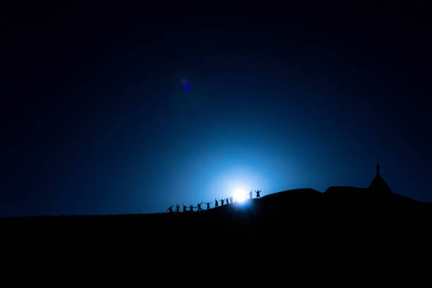 istock people on the horizon on the mountain with the moon behind 1296004715