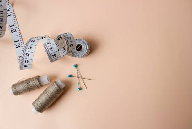 istock White measuring tape, needles and gold threads on a beige background. Sewing kit. 1296006499