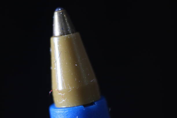 Macro photo of ballpoint pen tip with dark grey background. Extreme macro image of metal ballpoint pen on grey background.