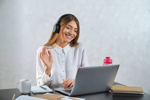 istock Woman waving and talking during online education on laptop 1296007385