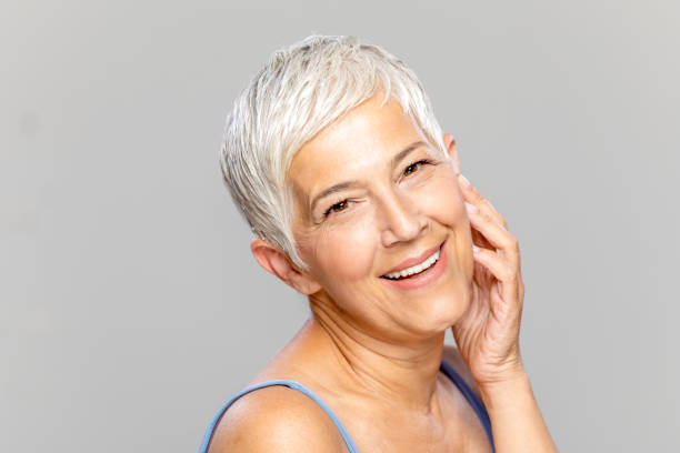 istock Happy senior woman against grey background. 1296007525