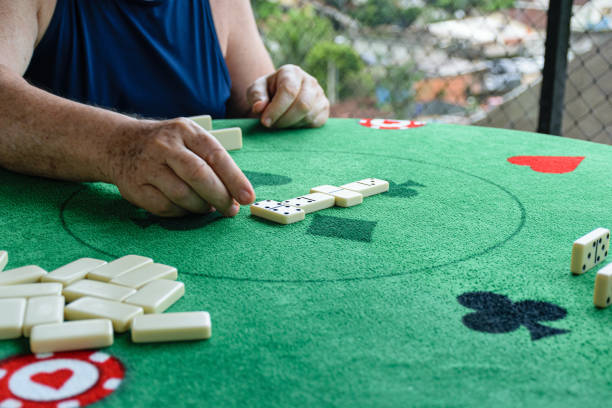 istock Elderly man placing a double 4 in the domino game. 1296009063