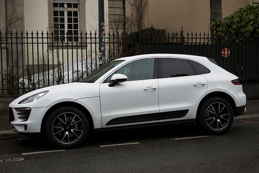 Mulhouse - France - 12 January 2021 -  Profile view of white Porsche Macan parked in the street by rainy day