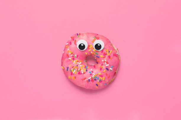 istock Shocked pink glazed doughnut donut on pink with googly eyes 1296011655