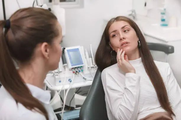 Attractive young woman having toothache, visiting dentist