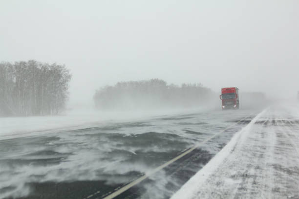 istock Transport moves along an asphalt road during a blizzard. 1296012053