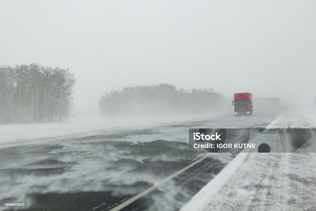 Transport moves along an asphalt road during a blizzard. Transport moves along an asphalt road Squall Stock Photo