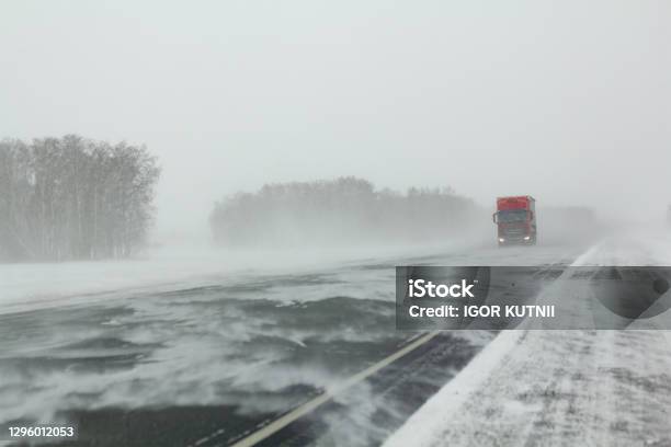 Transport Moves Along An Asphalt Road During A Blizzard Stock Photo - Download Image Now