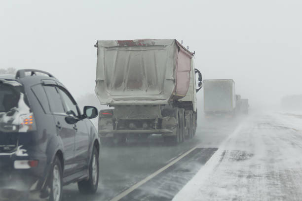 istock Transport moves along an asphalt road during a snow storm. 1296012055