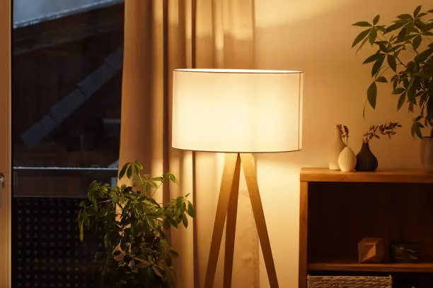 Photo of View of tripod lamp in a cozy living room spending warm light