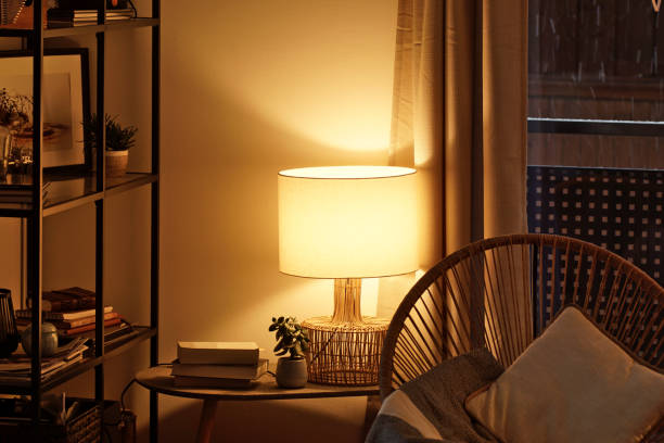 blick auf eine gemütliche leserecke mit einer tischlampe, die warmes licht ausgibt - brown table inside stock-fotos und bilder