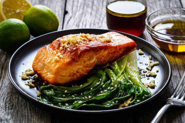 istock Fish dish - salmon steak with pak choi cabbage on wooden table 1296015278