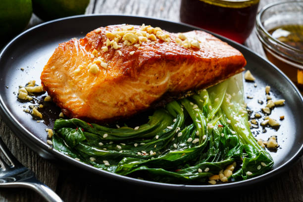 istock Fish dish - salmon steak with pak choi cabbage on wooden table 1296015300