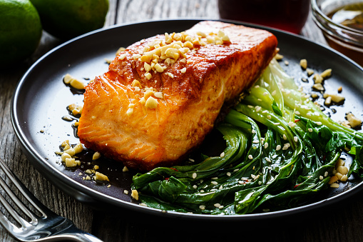 Fish dish - salmon steak with pak choi cabbage on wooden table