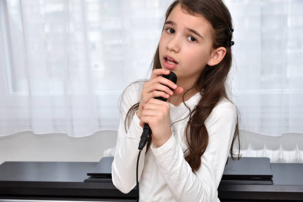 istock Young girl with a microphone singing 1296015984