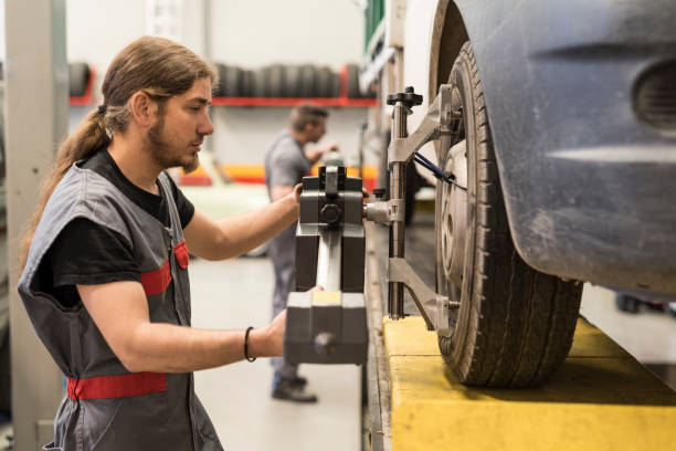 istock Mechanic calibrating wheels with computer and technology equipment. Manual adjustment 1296017561