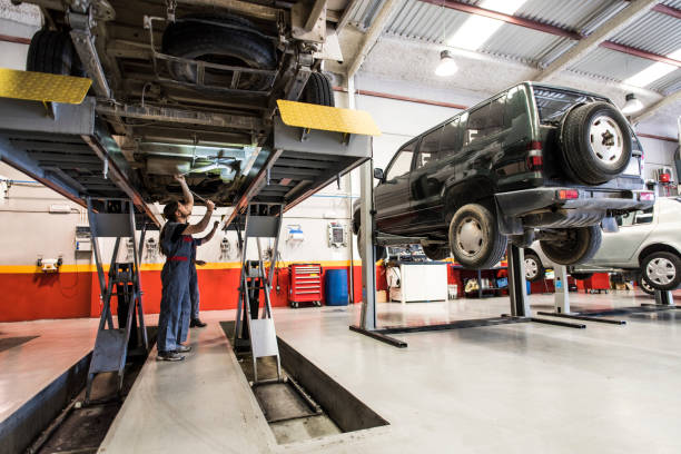 자동차 엘리베이터. 정비사는 산업용 자동차의 밑면을 점검하고 섀시와 차축을 리프팅 벤치에서 확인합니다. - mechanic auto repair shop auto mechanic repairing 뉴스 사진 이미지
