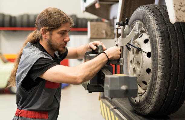 istock Mechanic calibrating wheels with computer and technology equipment. Manual adjustment 1296017616