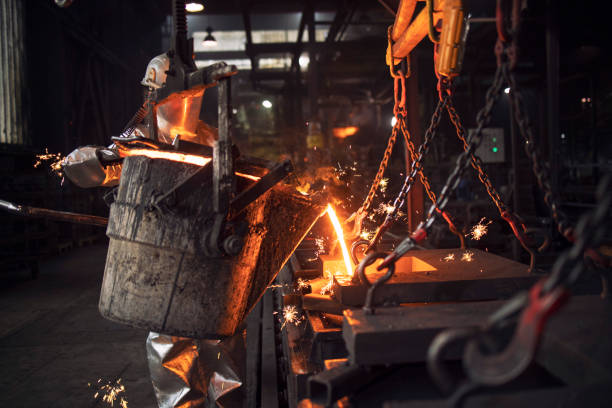 istock Worker in protection suit pouring liquid molten iron in foundry. 1296020155