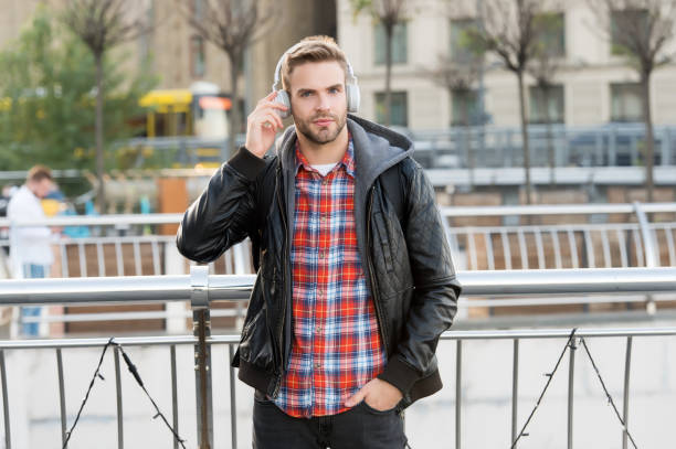 istock Self improve. Podcast for youth. Online education courses. Listen music. Student study use headphones. Handsome man enjoy music urban background. Distance education. Remote studying. Modern education 1296020534