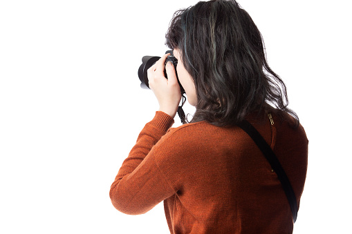 Side view of a female photographer holding a camera isolated on a white background for composites.  The model is posed to face a scenery or copy space