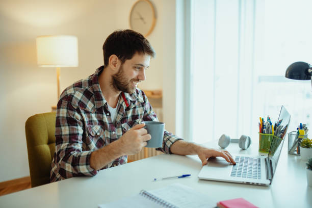 istock Businessman working from home on laptop and drinking coffee. Man working from home during coronavirus lockdown 1296020834