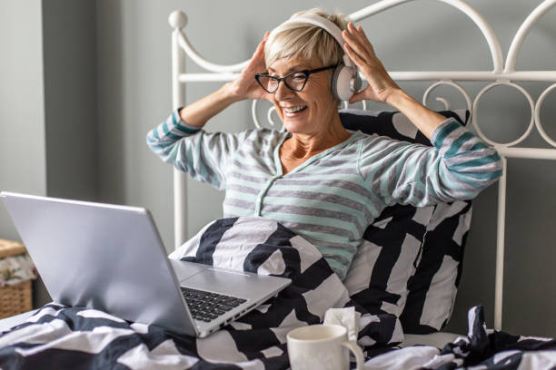 istock Senior woman laying in bed and using laptop 1296022003