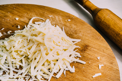 Three different kinds of Shredded cheese on a wooden board. The concept of cooking. Macro food photo close up